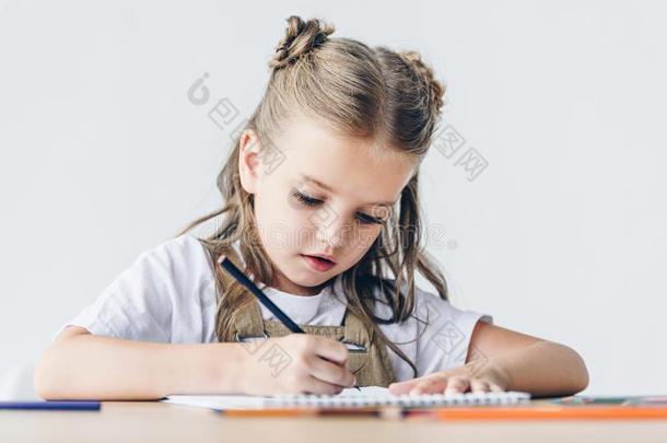 小的女学生绘画和颜色铅笔