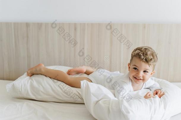 微笑的蹒跚行走的人男孩采用白色的<strong>紧身衣裤</strong>ly采用g向枕头向床