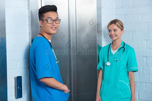 微笑的多种文化的医学的学生等候电梯