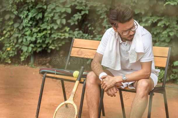 疲倦的网球演员和毛巾和网球球拍静止的向茶