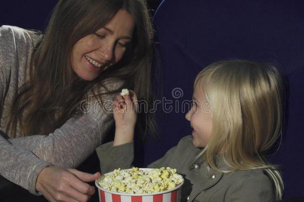 值得崇拜的小的女孩给食她妈妈和爆米花在指已提到的人电影院