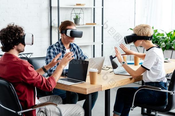 年幼的同事使用实质上的现实戴在头上的耳机或听筒和便携式电脑呜呜
