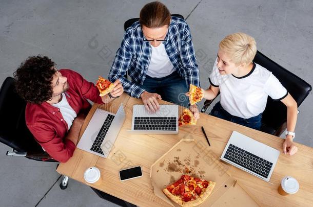上面的看法关于年幼的同事吃意大利薄饼和使用便携式电脑