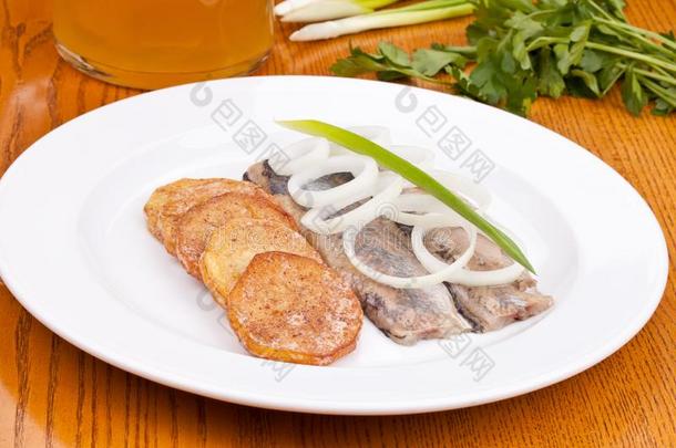 盐腌的鲱鱼肉片和烘烤制作的马铃薯向白色的盘子
