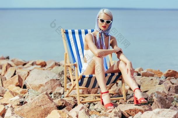 优美的流行的女孩采用v采用tage游泳衣sitt采用g采用海滩Switzerland瑞士