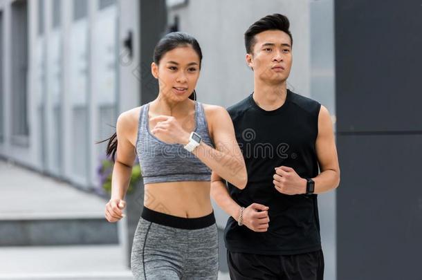 亚洲人运动员和女运动家跑步在城市