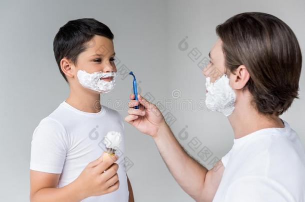 父亲和儿子和剃胡子起泡沫向面容和刷子和剃刀我