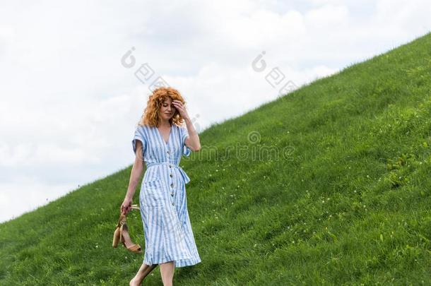 有魅力的红发的人女人运送的鞋子向长满草的