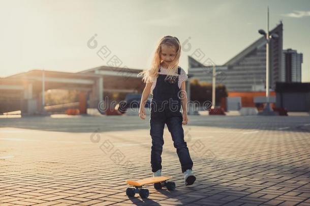 微笑的值得崇拜的小孩起立和滑板在停放