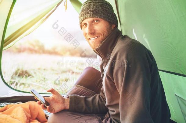 有胡须的旅行支票男人用途他的可移动的电话一次采用帐篷