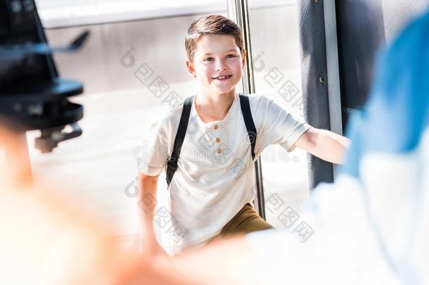 微笑的男生进<strong>入学</strong>校公共汽车和有样子的