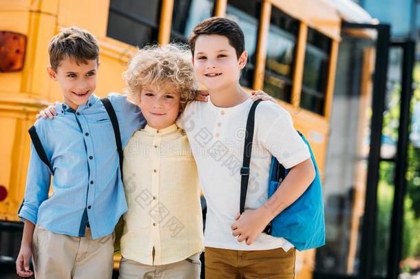 值得崇拜的小的男生拥抱采用前面关于学校公共汽车和