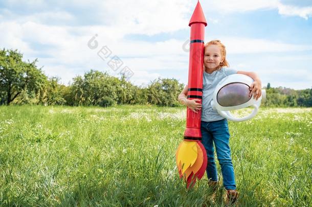 微笑的红色的头发小孩和火箭和宇航员头盔st和ing