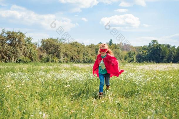 小的小孩采用红色的超级英雄斗篷和面具runn采用g采用草地