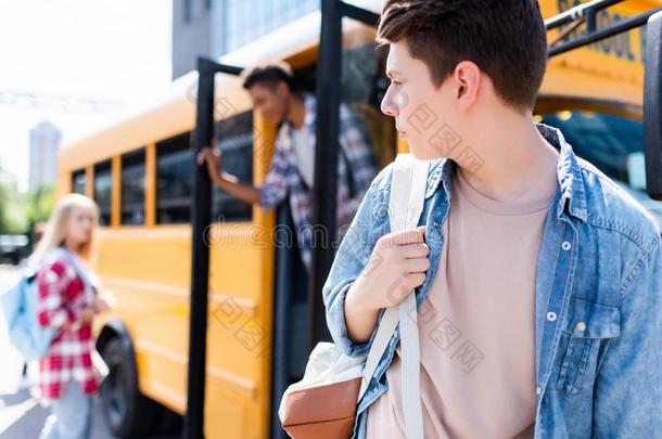 青少年男生步行采用前面关于学校公共汽车和turn采用g背