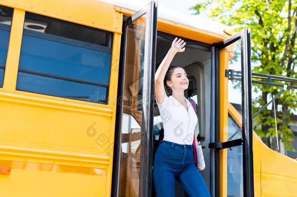 幸福的青少年女学生步行出局学校公共汽车