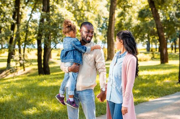 非洲的美国人双亲和女儿步行同时采用公园