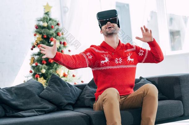 幸福的男人做手势和使用VirtualReality虚拟现实戴在头上的耳机或听筒圣诞节树