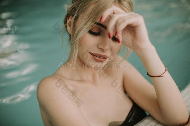 漂亮的年幼的女人令人轻松的向指已提到的人游泳池边