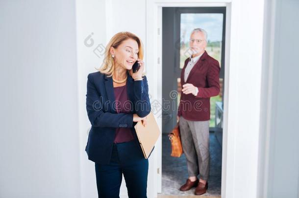 白肤金发碧眼女人-有毛发的真的财产经纪人说话在旁边电话和她secuting起诉