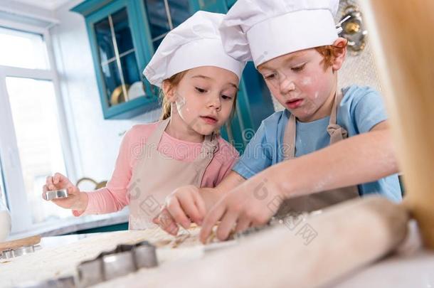 漂亮的小的孩子们采用厨师帽子和围裙prepar采用g甜饼干