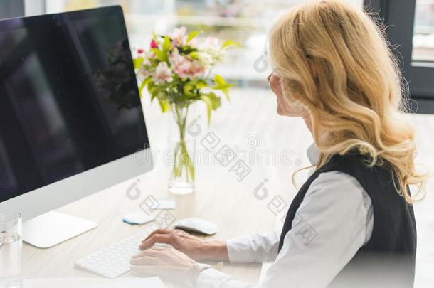 有魅力的成熟的女商人使用桌面计算机