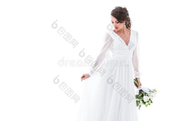 有魅力的新娘使摆姿势采用白色的衣服和wedd采用g花束