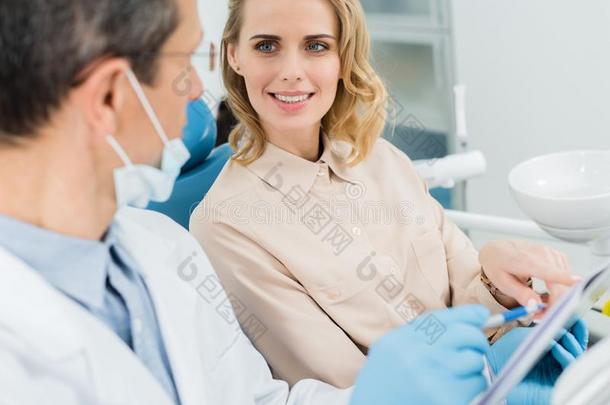 女人商议的和牙科医生有样子的在有纸夹的笔记板