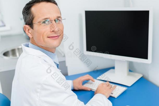 微笑的医生采用眼镜work采用g在旁边计算机