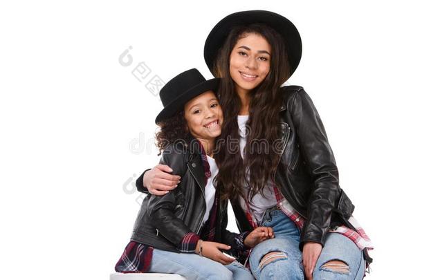 拥抱时髦的母亲和女儿采用帽子