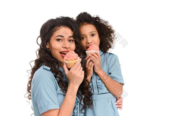 母亲和女儿吃美味的纸杯蛋糕和乳霜