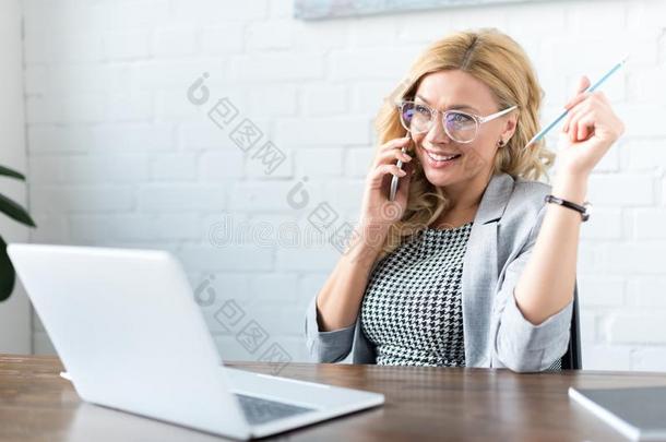 幸福的女商人讲话在旁边智能手机采用办公室