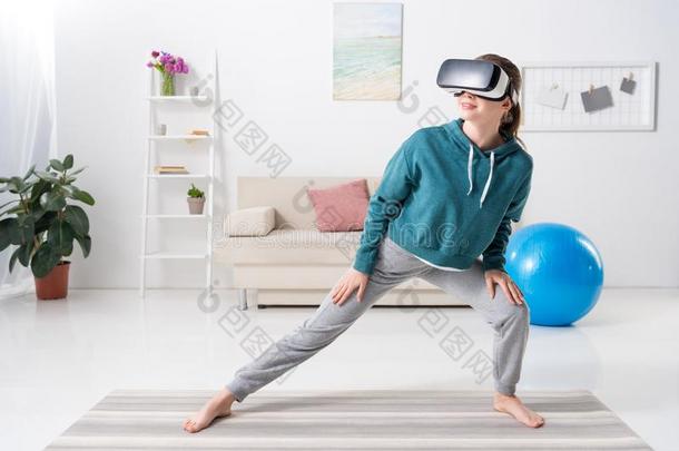 女孩伸木头支架和实质上的现实戴在头上的耳机或听筒向瑜伽席子