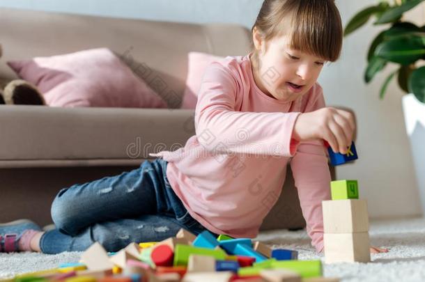 小孩和下综合征演奏和玩具立方形的东西向地面