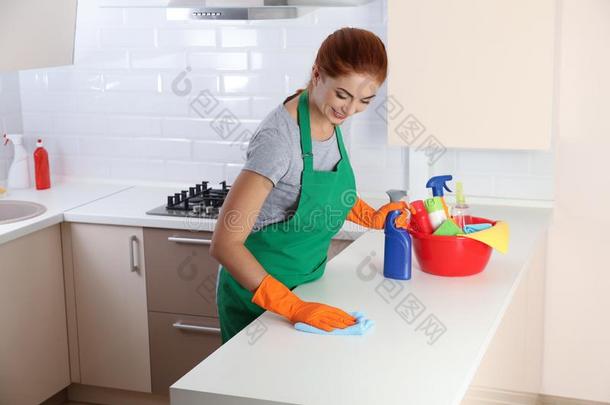 女人采用保护的拳击手套clean采用g厨房表和破布