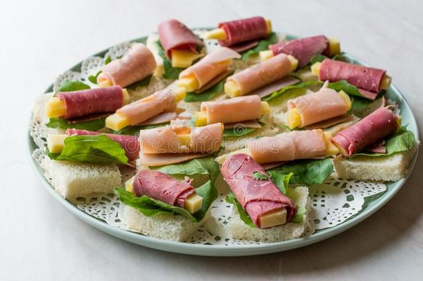 夹鱼子或小鱼的烤面包火腿有包装的和奶酪和绿叶蔬菜采用圆形的盘子.