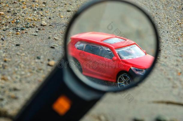 玩具模型红色的汽车关-在上面向湿的沙在下面关-在上面放大镜
