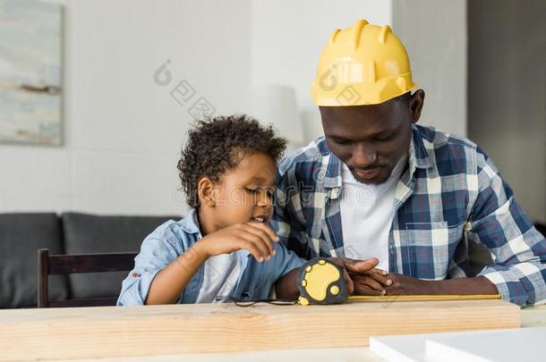 幸福的非洲的-美国人父亲和儿子量木板关于木材