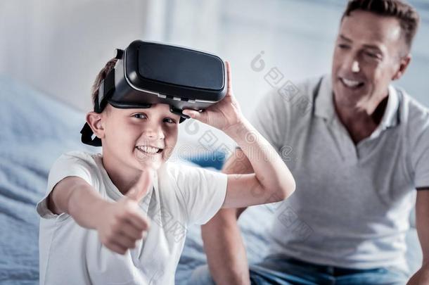 满意的可爱的男孩放置从落下指已提到的人VirtualReality<strong>虚拟现实</strong>眼镜和<strong>微笑</strong>的.