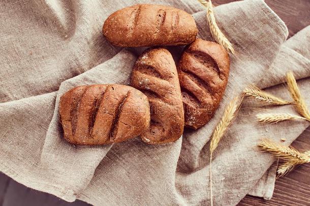 新近烘烤制作的圆形的小面包或点心和小穗关于小麦说谎向一亚麻布布