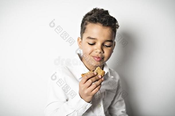 黑的男孩吃饼干越过白色的背景