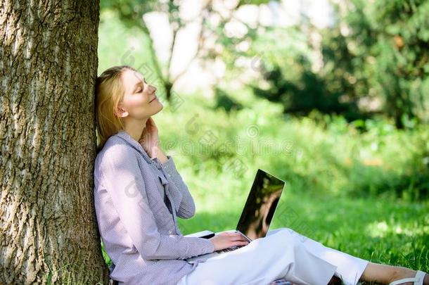 女人和便携式电脑使工作在户外倾斜树.分为轻松.Educationalinstitutions教研机构
