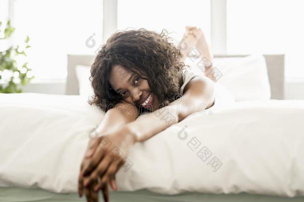美丽的黑的女人向一白色的床