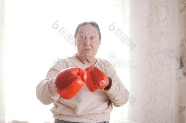 一老的较高的女人拳击采用红色的拳击手套,look采用g侵略地英语字母表的第6个字母
