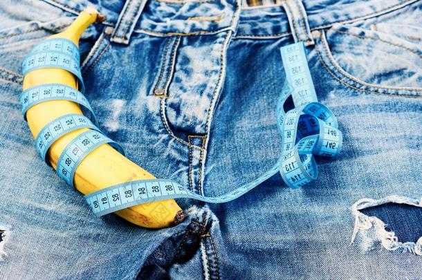 香蕉有包装的和蓝色测量带子向牛仔裤胯部