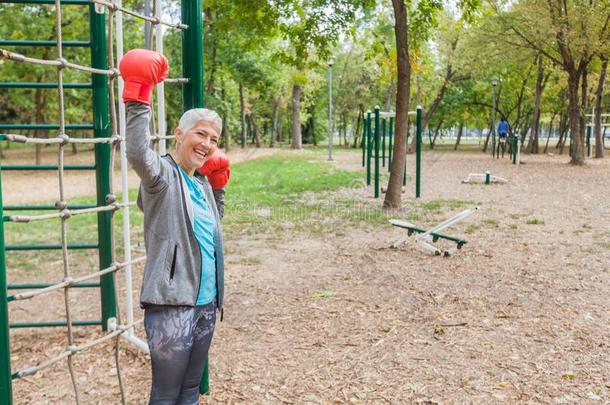 健康的较高的女人和拳击手套在户外的健康公园