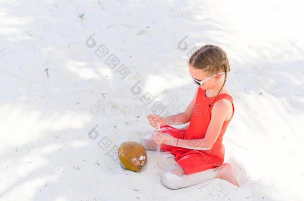 小的值得崇拜的女孩和<strong>大</strong>的<strong>椰子</strong>向白色的沙的海滩