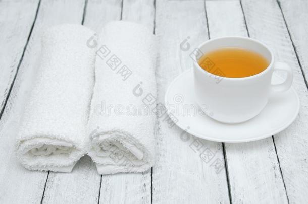 白色的杯子和茶杯托关于绿色的茶水和两个白色的毛巾布毛巾向