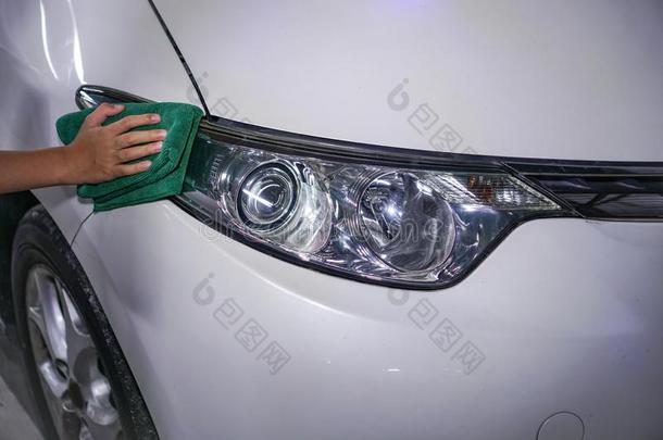 手清洁汽车的前灯向一白色的汽车