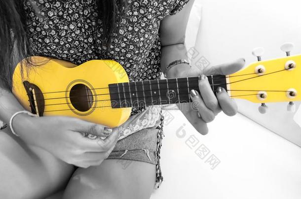 女士演奏小的吉他,黄色的夏威夷的四弦琴详述和关在上面